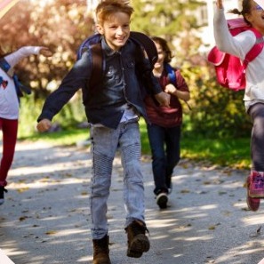 Blije kinderen met rugzakken rennen lachend naar school